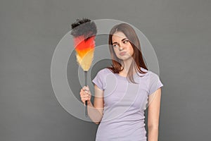 Freestyle. Young girl standing isolated on grey looking at brush for cleaning pouting lips playful