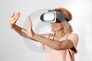 Freestyle. Young woman in virtual reality headset standing isolated on grey touching air excited close-up