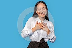 Freestyle. Young woman wearing shirt and skirt standing  on blue touching chest laughing touched