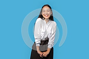 Freestyle. Young woman wearing shirt and skirt standing isolated on blue closed eyes laughing cheerful having fun