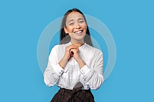 Freestyle. Young woman wearing shirt and skirt standing isolated on blue holding hands together lovely