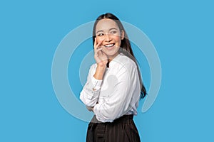 Freestyle. Young woman wearing shirt and skirt standing isolated on blue touching face laughing joyful