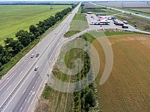 Freeway road with exit to petrol station, wide and straight highway in plain terrain, aerial view