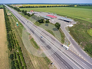 Freeway road with traffic lay-by to petrol station, wide and straight highway in plain terrain, view from above