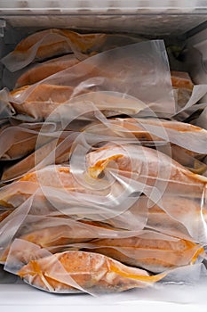 Freeze cooked salmon in vacuum packs in freezer of modern refrigerator, concept of food preservation