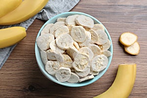 Freeze dried and fresh bananas on wooden table, flat lay