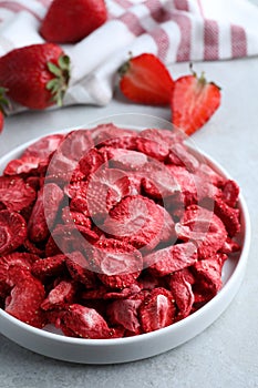 Freeze dried and fresh strawberries on light grey table, closeup