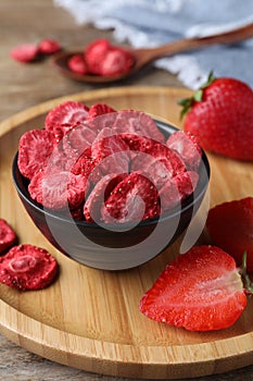 Freeze dried and fresh strawberries on wooden table, closeup