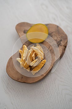 Freeze-dried mango with fresh one on olive wood board