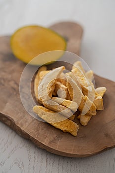 Freeze-dried mango with fresh one on olive wood board