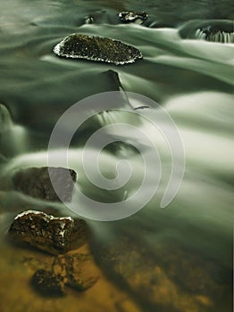 Freeze mossy sandstone boulder in dark cold water