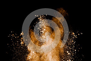 Freeze motion of brown dust explosion.Stopping the movement of brown powder. Explosive brown powder on black background