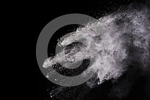 Freeze motion of white color powder exploding on black background.