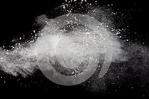 Freeze motion of white dust particles splash on black background.White powder explosion clouds