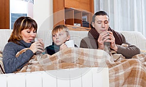 Freezing family of three warming near warm radiator