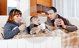 Freezing parents and teenage son warming near warm calorifer