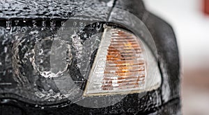 Freezing rain ice coated car. Headlight and signal light on black car covered in freezing rain. Bad driving weather. photo