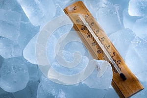 Freezing temperatures and cold weather concept with a vintage thermometer surrounded by blue ice showing sub zero temperature with
