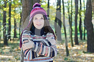 Freezing young woman wearing knitted woolly hat and embracing herself