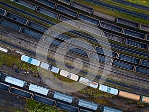 Freight cargo wagons train on bend of railway tracks, concept delivery. Aerial top view