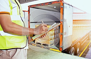 Freight industry warehouse shipments transport. Worker courier holding clipboard inspecting checklist load cargo into a truck.