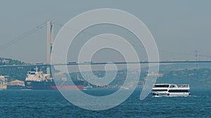 Freight ship sailing under Bosphorus Bridge, ferry ships and boats moving