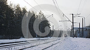 A freight train arrives at the station on a sunny winter day.