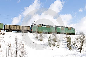 Freight train with electric locomotive moving by railways in winter