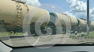 A freight train with liquid tanks and freight cars passes a railway intersection.