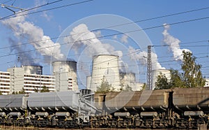 Freight train and a power plant with smoking chimneys