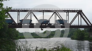 Freight train rides on a railway bridge over the river