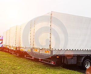 Freight vans stand in a row, rear view, trucking industry and sun