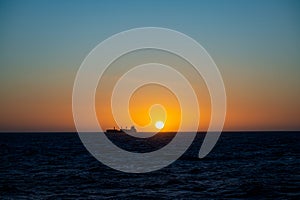 Freighter in sunset on the sea, South Pacific Ocean, cargo ship at sunset on ocean.