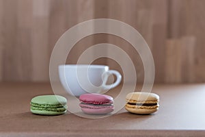 Frence sweet delicacy macaroons and white coffee cup on grunge wood background
