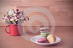 Frence sweet delicacy macaroons and white coffee cup on wood background