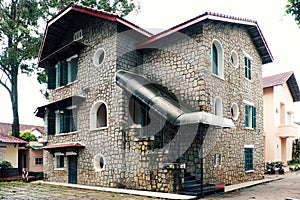 French architecture of ancient stone house with green wooden window and door at Da Lat