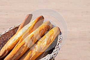 French baguette in rustic wooden basket on brown background