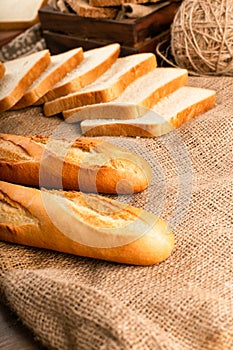 French baguette with slices of bread on tablecloth