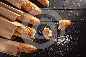 French baguettes with sesame seed on black wooden background