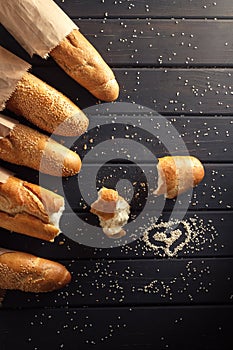 French baguettes with sesame seed on black wooden background