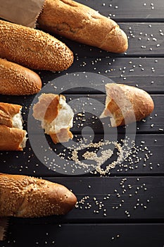 French baguettes with sesame seed on black wooden background