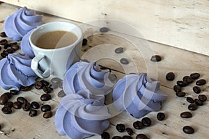 French blue meringue cookies and cup of coffee on wooden background