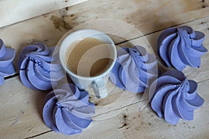 French blue meringue cookies and cup of coffee on wooden background