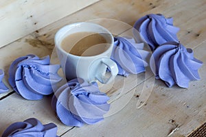 French blue meringue cookies and cup of coffee on wooden background