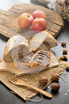 French bread baguette cut on wooden board with knife. with a chocolate butter and red apple.