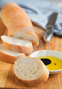French bread baguette cut on wooden bread board and olive oil.