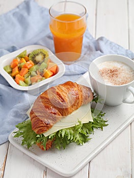 French breakfast: croissant sandwich with cheese, fruit salad, and coffee