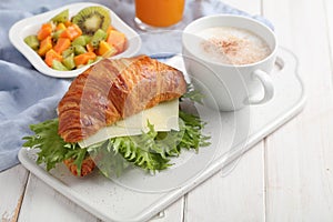 French breakfast: croissant sandwich with cheese, fruit salad, and coffee