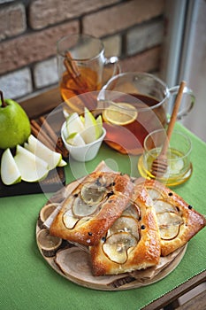 French brioche bun with pear, honey and tea on wooden table