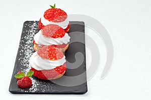 French Cakes with strawberry cream shanti. aery brewing cake on black shale. Restaurant composition on white background.